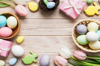 Yumurtalı Paskalya çerçevesi, renkli bir arka planda hediye kutusu ve lale. Minimum konsept. Üst Manzara Mutlu Paskalyalar kompozisyonu. Metin için yerin bir kopyasına sahip kart.