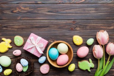 Yumurtalı Paskalya çerçevesi, renkli bir arka planda hediye kutusu ve lale. Minimum konsept. Üst Manzara Mutlu Paskalyalar kompozisyonu. Metin için yerin bir kopyasına sahip kart.