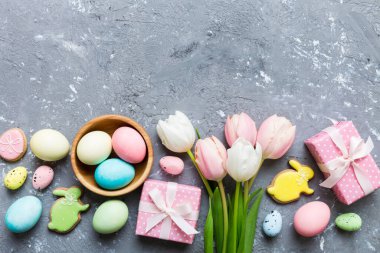 Yumurtalı Paskalya çerçevesi, renkli bir arka planda hediye kutusu ve lale. Minimum konsept. Üst Manzara Mutlu Paskalyalar kompozisyonu. Metin için yerin bir kopyasına sahip kart.