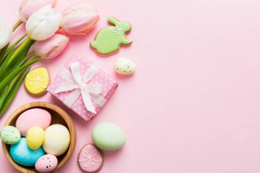 Yumurtalı Paskalya çerçevesi, renkli bir arka planda hediye kutusu ve lale. Minimum konsept. Üst Manzara Mutlu Paskalyalar kompozisyonu. Metin için yerin bir kopyasına sahip kart.