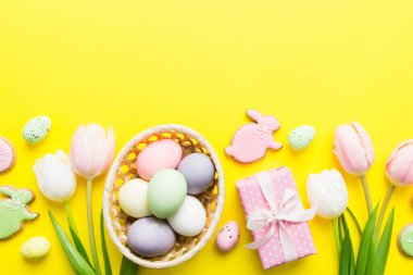 Yumurtalı Paskalya çerçevesi, renkli bir arka planda hediye kutusu ve lale. Minimum konsept. Üst Manzara Mutlu Paskalyalar kompozisyonu. Metin için yerin bir kopyasına sahip kart.