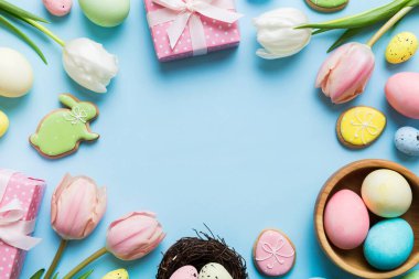 Yumurtalı Paskalya çerçevesi, renkli bir arka planda hediye kutusu ve lale. Minimum konsept. Üst Manzara Mutlu Paskalyalar kompozisyonu. Metin için yerin bir kopyasına sahip kart.