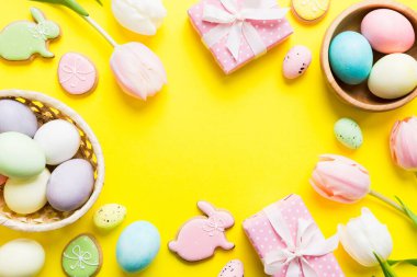 Yumurtalı Paskalya çerçevesi, renkli bir arka planda hediye kutusu ve lale. Minimum konsept. Üst Manzara Mutlu Paskalyalar kompozisyonu. Metin için yerin bir kopyasına sahip kart.