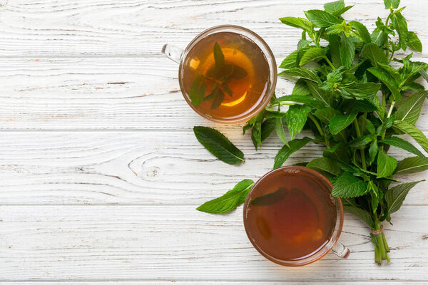 Чашка мятного чая на фоне стола. Зеленый чай со свежим мятным видом сверху с копировальным пространством.