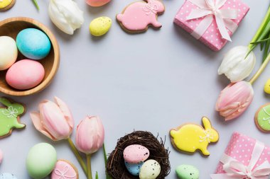Yumurtalı Paskalya çerçevesi, renkli bir arka planda hediye kutusu ve lale. Minimum konsept. Üst Manzara Mutlu Paskalyalar kompozisyonu. Metin için yerin bir kopyasına sahip kart.