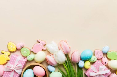 Yumurtalı Paskalya çerçevesi, renkli bir arka planda hediye kutusu ve lale. Minimum konsept. Üst Manzara Mutlu Paskalyalar kompozisyonu. Metin için yerin bir kopyasına sahip kart.