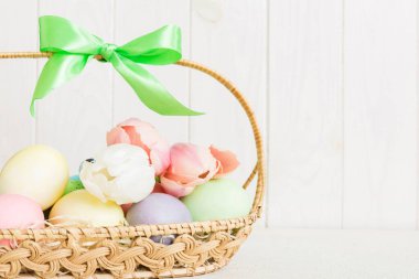 Mutlu Paskalya kompozisyonu. Renkli masada sarı laleli sepetli Paskalya yumurtaları. Fotokopi alanı olan doğal renkli yumurtalar.
