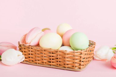 Mutlu Paskalya kompozisyonu. Renkli masada sarı laleli sepetli Paskalya yumurtaları. Fotokopi alanı olan doğal renkli yumurtalar.