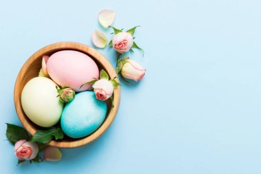 Mutlu Paskalyalar. Renkli masada sarı güllerle birlikte Paskalya yumurtaları. Doğal boyalı renkli yumurtalar arkaplan arkaplan görünümü kopya alanı ile.