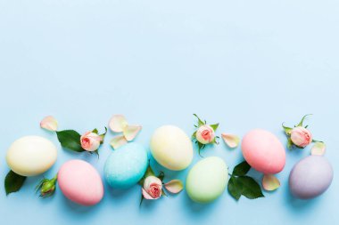 Mutlu Paskalyalar. Renkli masada sarı güllü Paskalya yumurtaları. Doğal boyalı renkli yumurtalar arkaplan arkaplan görünümü kopya alanı ile.