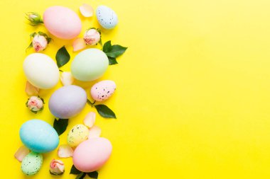 Mutlu Paskalyalar. Renkli masada sarı güllü Paskalya yumurtaları. Doğal boyalı renkli yumurtalar arkaplan arkaplan görünümü kopya alanı ile.