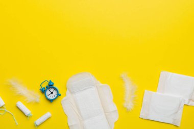 Alarm saatini hijyenik kadın tamponları ve regl pedleri ile çalıyor. Tıbbi konsept kadın kritik günler ve regl dönemi. Kadın günlük hijyen. Boşluğu kopyala.