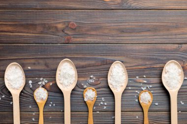 Ahşap arka planda bir sürü tahta kaşıkta tuz. Farklı tuzlu kaşıklar..
