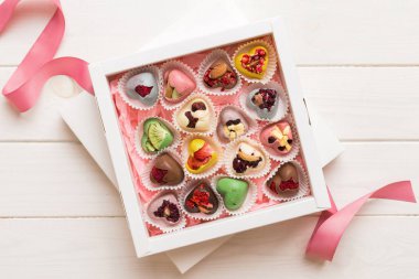 Holiday composition: sweet candy, with gift boxes with bow and chocolate hearts, photo template, background. Top View with copy space on colored background.