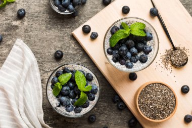 Sağlıklı kahvaltı ve chia tohumlu vanilyalı puding ve böğürtlenli masa arkası, vejetaryen gıda, diyet ve sağlık konsepti. Hindistan cevizi sütü ve yabanmersinli Chia pudingi..