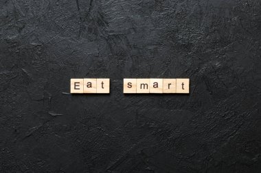 Ahşap blokta yazan akıllı kelimeyi ye. Üst görünüm konseptiniz için çimento masasında akıllı metin yiyin.