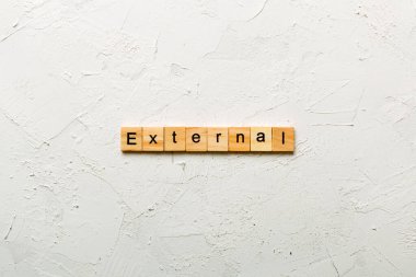 Tahta blokta EXTERNAL kelimesi yazıyor. Deksing, konsept için EXTERNAL metin çimento tablo üzerinde.
