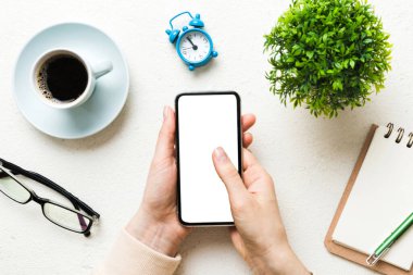 Mesajınız veya bilgi içeriğiniz için boş bir kopya ekranı olan akıllı telefonları tutan kadın ellerinin üst görünümü. üst görünümde telefon beyaz ekranı kullanan kadın eli.