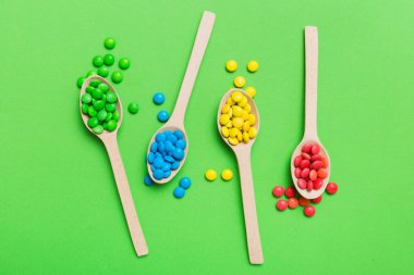 Renkli arka planda kaşık üzerinde renkli tatlı şekerler. Fotokopi alanı ile şekerleme dekoru üst görünümü.