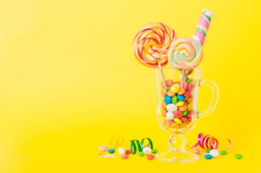 Masanın üzerinde açık arkaplanda renkli şekerler. Büyük kıvrımlı lolipoplar. Şekerci dükkanından leziz şekerlerle dolu yaratıcı bir kavanoz konsepti.