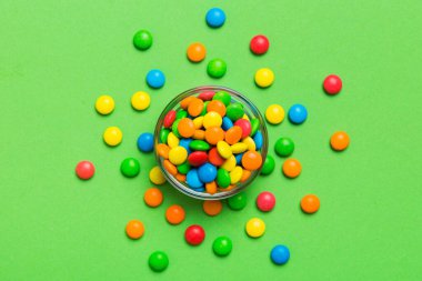 Renkli arka planda bir kasede çok renkli şekerler. Doğum günü ve tatil konsepti. Kopyalama alanı olan üst görünüm.