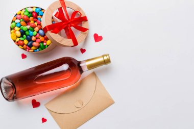 Sevgililer Günü için renkli arka planda bir şişe kırmızı şarap hediye ve çikolatalı. Kalp, hediye kutusuyla şekillendirilmiş çikolatalar fotokopi alanı ile üst görünüm.