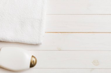 Kozmetik şampuan şişesi renkli bir masada havluyla birlikte. Banyo arka planı, el ve vücut bakımı için tuvalet aksesuarları..