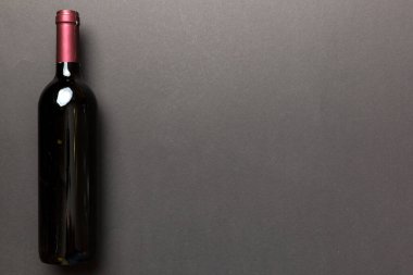 Renkli masada bir şişe kırmızı şarap. Düz konum, üst görünüm kopyalama alanı.