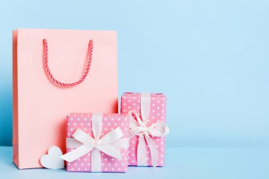 Shopping bag with gift box on colored background perspecrive view. Space for text holiday concept.
