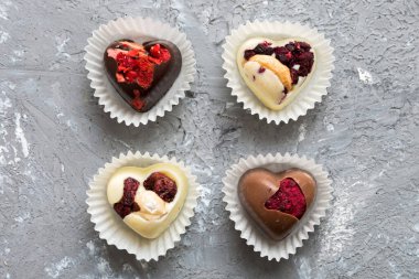 chocolate sweets in the form of a heart with fruits and nuts on a colored background. top view with space for text, holiday concept.
