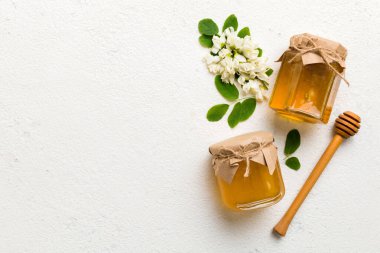 Akasya çiçekli ve yapraklı bal kavanozu. Taze bal üst görünüm düz yatıyordu.