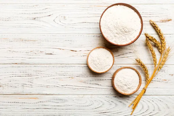 Tahta kasede buğday unu ve renkli arka planda buğday dikenleri. dünya buğday krizi.