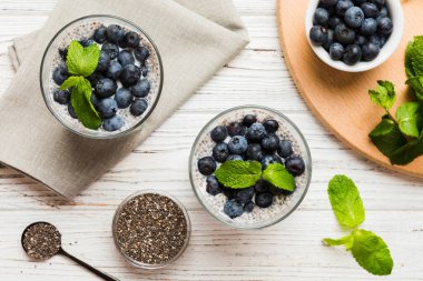 Sağlıklı kahvaltı ve chia tohumlu vanilyalı puding ve böğürtlenli masa arkası, vejetaryen gıda, diyet ve sağlık konsepti. Hindistan cevizi sütü ve yabanmersinli Chia pudingi..