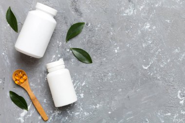 Omega-3 kapsülleri yeşil yapraklı arka planda beyaz bir şişede yatar. Balık yağı tabletleri. Biyolojik olarak aktif katkı maddeleri. Omega 6, Omega 9, A vitamini, E, D vitamini, D3 vitamini..