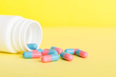 Renkli arka planda haplarla dolu plastik ilaç şişesi. İnternetteki eczane. Ağrı kesici ilaç ve antibiyotik ilaç direnci konsepti. İlaç endüstrisi..