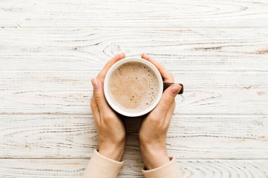 Renkli arka planda bir fincan kahve tutan minimalist stil bir kadın. Düz yerde, kapuçino bardağının üstünde. Metin için boş yer, kopyalama alanı. Kahve bağımlılığı. Üst manzara, düz uzanma.