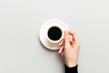 Renkli arka planda bir fincan kahve tutan minimalist stil bir kadın. Düz yatıyordu, üstten espresso fincanı. Metin için boş yer, kopyalama alanı. Kahve bağımlılığı. Üst manzara, düz uzanma.