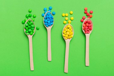 Renkli arka planda kaşık üzerinde renkli tatlı şekerler. Fotokopi alanı ile şekerleme dekoru üst görünümü.