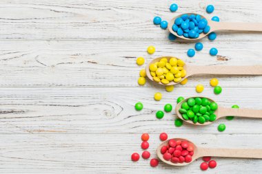 Renkli arka planda kaşık üzerinde renkli tatlı şekerler. Fotokopi alanı ile şekerleme dekoru üst görünümü.