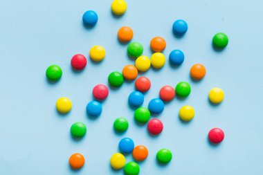 Renkli arka planda karışık renkli şeker koleksiyonu. Düz yerde, üst tarafta. Renkli çikolata kaplı şeker çerçevesi.