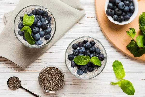 Sağlıklı kahvaltı ve chia tohumlu vanilyalı puding ve böğürtlenli masa arkası, vejetaryen gıda, diyet ve sağlık konsepti. Hindistan cevizi sütü ve yabanmersinli Chia pudingi..