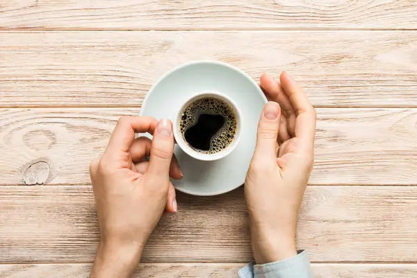 Renkli arka planda bir fincan kahve tutan minimalist stil bir kadın. Düz yerde, kapuçino bardağının üstünde. Metin için boş yer, kopyalama alanı. Kahve bağımlılığı. Üst manzara, düz uzanma.