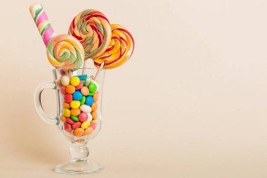 Masanın üzerinde açık arkaplanda renkli şekerler. Büyük kıvrımlı lolipoplar. Şekerci dükkanından leziz şekerlerle dolu yaratıcı bir kavanoz konsepti.