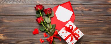 Zarflı sevgililer günü kompozisyonu, gül çiçeği ve kırmızı kalp masada. Üst manzara, düz yatış. Tatil kavramı.