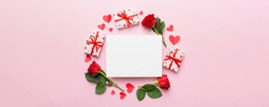 Renkli arka planda gül, oyuncak kutusu, kalp ve boş tebrik kartı modelinden yapılmış bir çerçeve. Top view, flat lay, copy space Holiday, Anneler Günü, doğum günü konsepti.