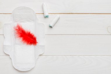 Kadın pedleri ve tamponları. Pembe ve menekşe arka planda izole edilmiş bir arka planda hijyenik pedlerin yanında uzanıyor. Kadın hijyeni ve adet dönemi konsepti.