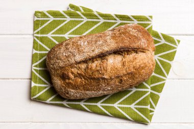 Taze ev yapımı tam buğday ekmeği. Peçetedeki ekmek kırsal arka planda, taze ekmek üst görünümü.