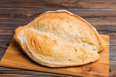 Tahtanın üzerinde beyaz ahşap zemine karşı taze pişmiş ekmek. Ekmeği kopyalama alanı ile perspektif görünümü.