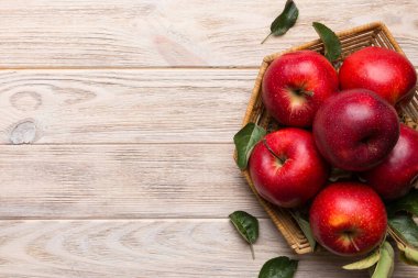 Tahta masada yeşil yapraklı taze kırmızı elmalar. Ahşap arka planda. Metin için üst görünüm boş alanı.