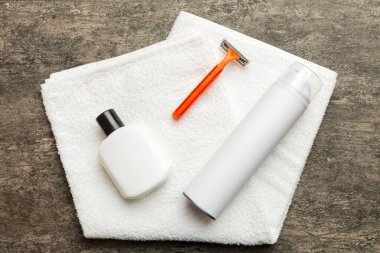 Tıraş Adam seti. Traş makinesi, havlu, losyon ve renkli arka planda tıraş köpüğü. Erkekler banyo aksesuarları üst görünüm.